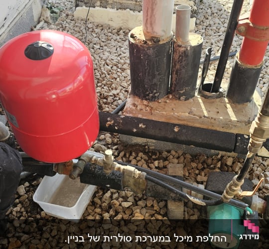 אדם עובד על דוד שמש עם מיכל אדום וצינורות.